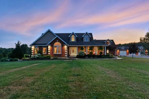 Exterior of a brick bungalow at dusk with the lights on